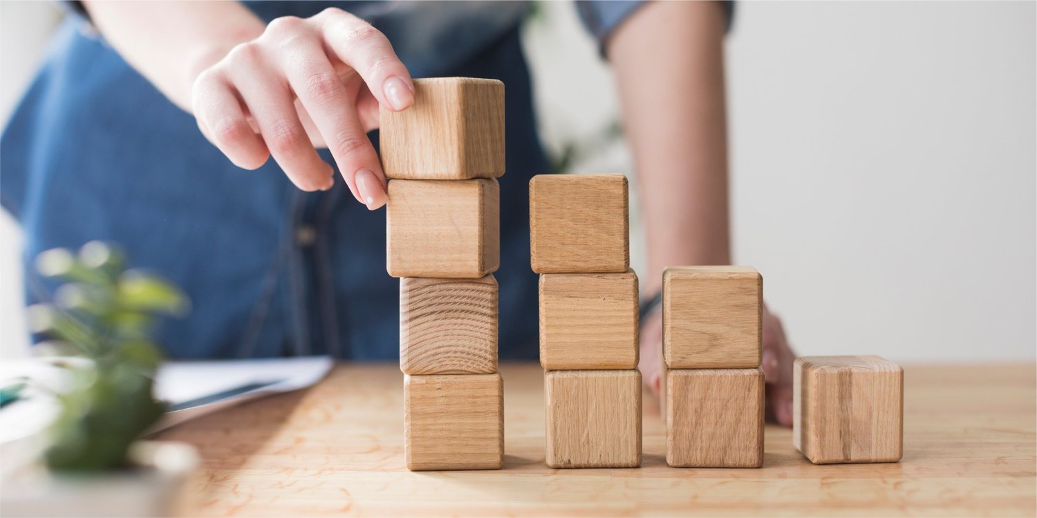 close-up-female-hand-stacking-wooden-block-desk-office_Blog copy