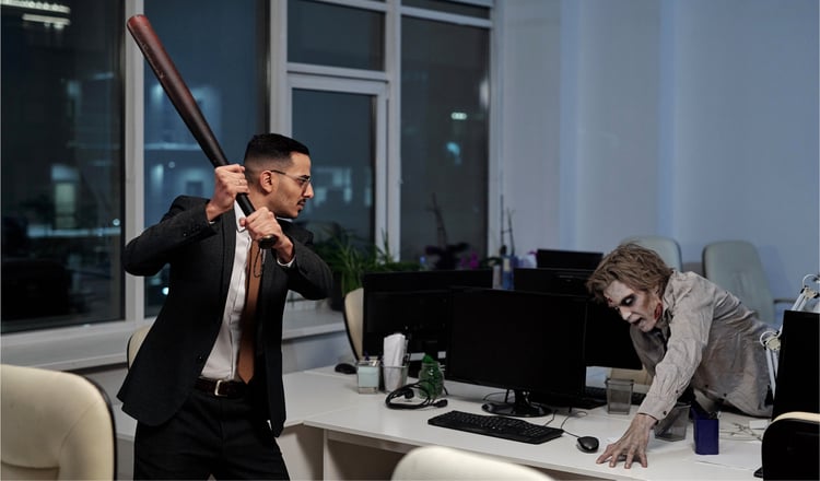 young-angry-businessman-with-baseball-bat-going-hit-spooky-man-with-zombie-greasepaint-his-face-hands-trying-get-upon-desk_NBLOG