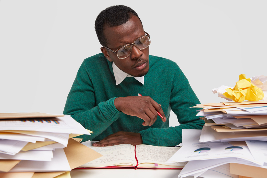 attentive-dark-skinned-man-big-eyewear-looks-seriously-pie-chart-writes-report-after-studying-documentation-dressed-green-jumper-isolated-white-background-people-botkeeper
