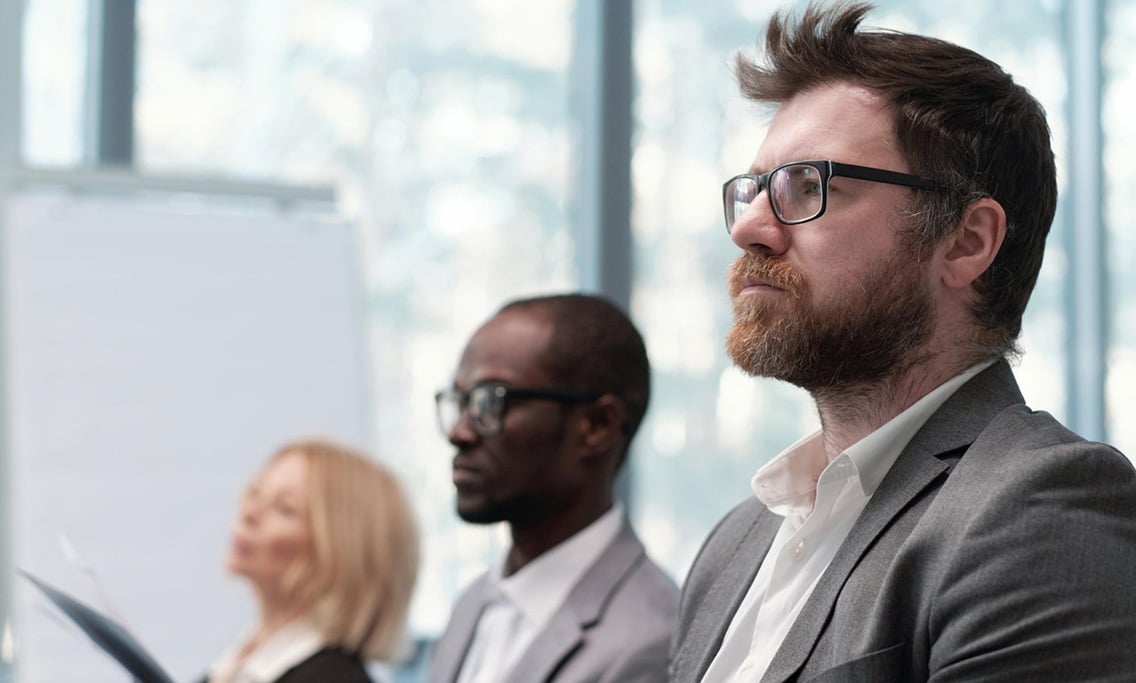 young-serious-bearded-businessman-looking-speaker-during-presentation-botkeeper