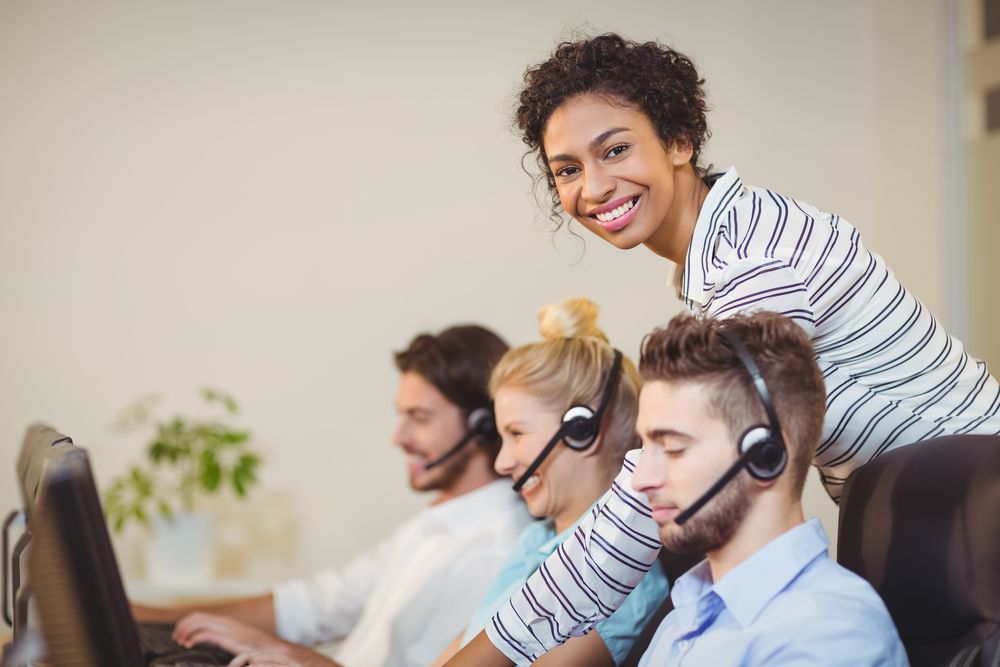 Portrait of smiling businesswoman with employees in call center