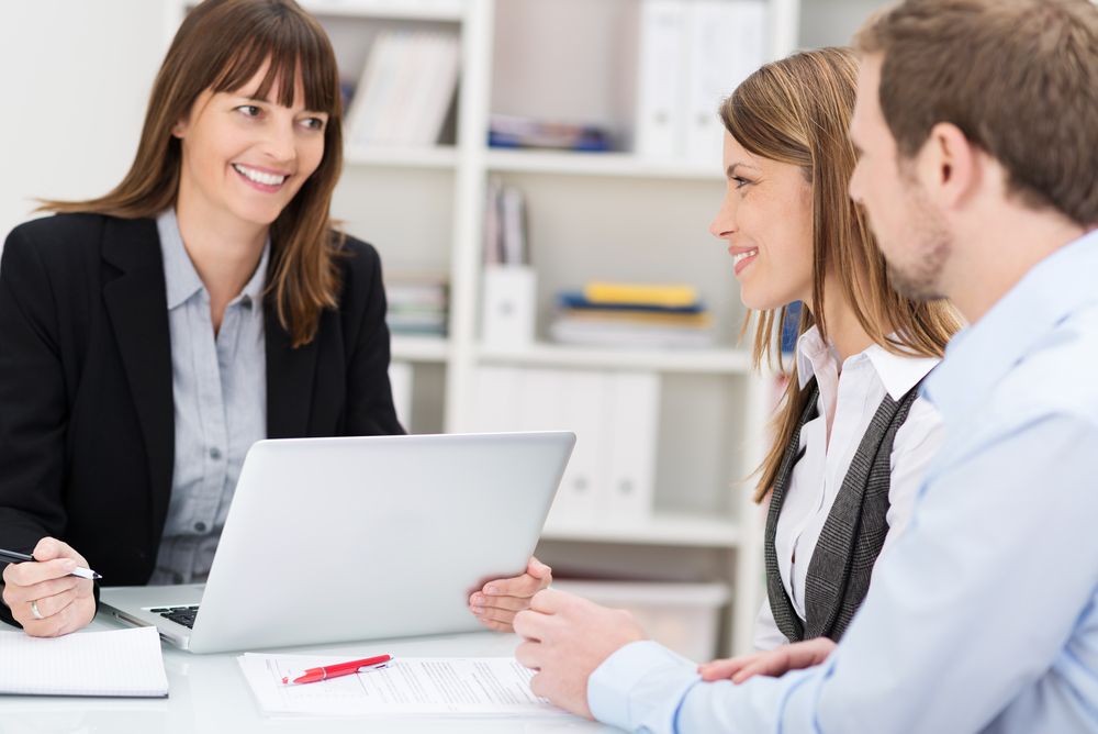 Young couple sitting in an office talking to a woman broker or investment adviser_Building CAS in 2021: What Your Firm Needs to Know to Get Started_Botkeeper