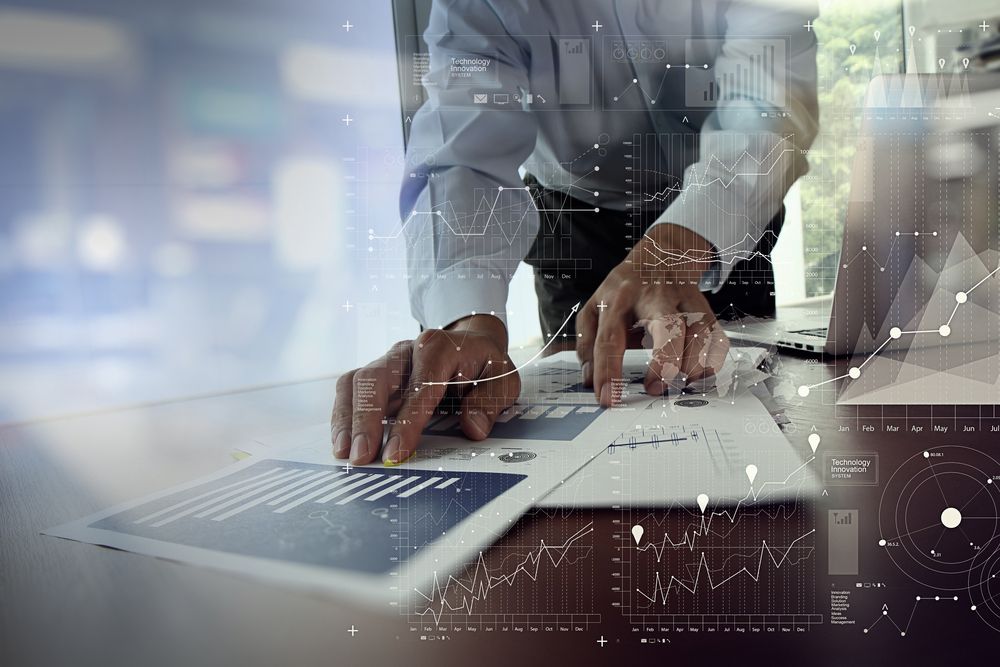 close up of businessman hand working on laptop computer with financial business graph information diagram on wooden desk as concept-1