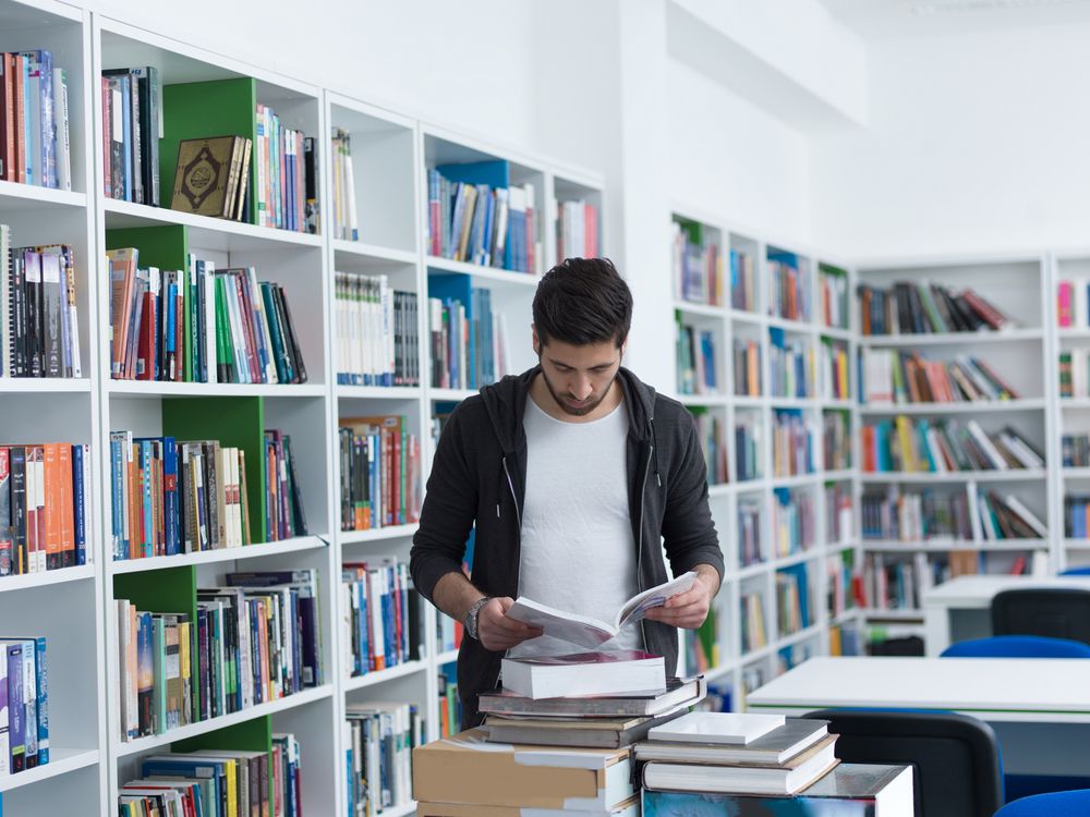 portrait of student in collage school library, arab youth learning and reading book